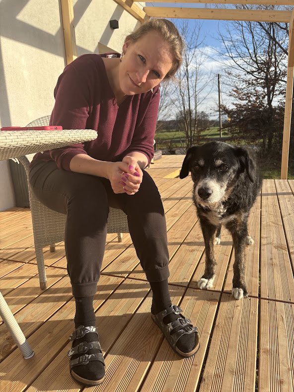 Hundebesitzerin mit ihrem Hund auf der Terrasse eines Hauses im Isar-Loisachtal